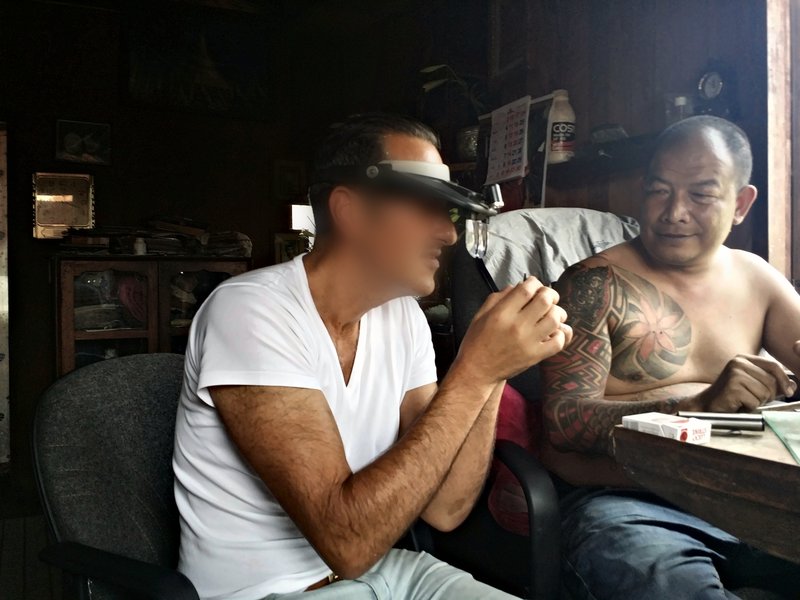 David Nataf taille un saphir avec Ku Pion, Mogok, 2016, loupe frontale sur les yeux, dans son atelier